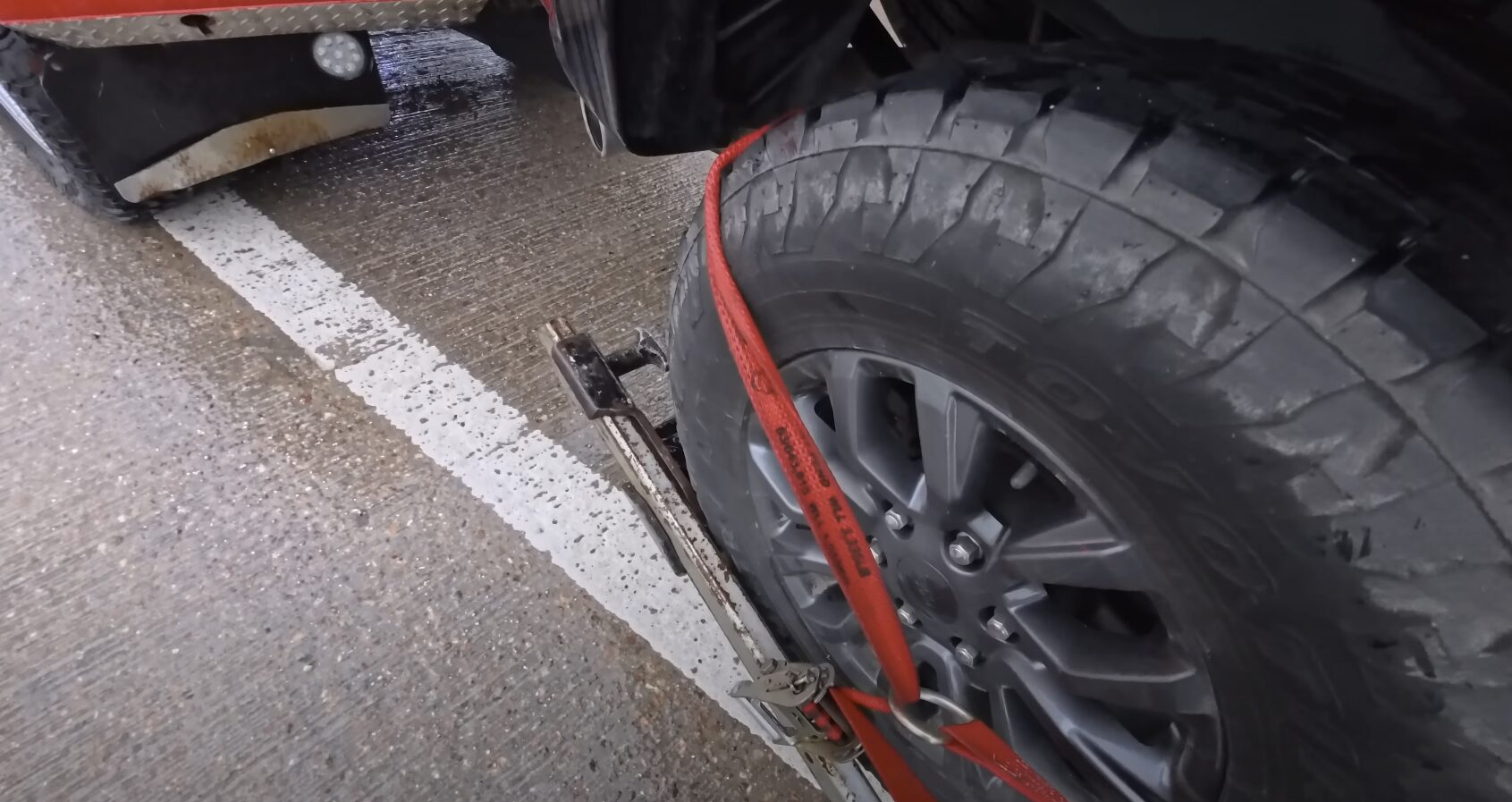 Professional towing service securing vehicle with safety straps